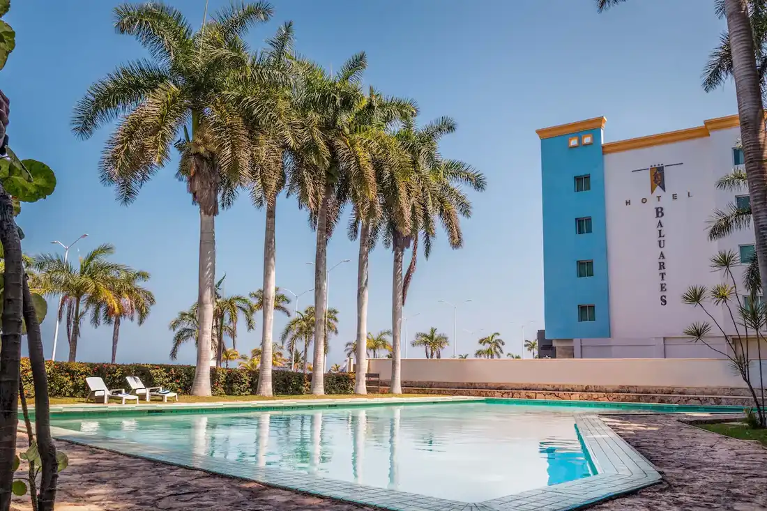 Outdoor pool surrounded by palm trees at Hotel Baluartes